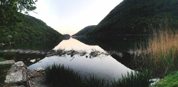 Scenic view of river by mountains against clear sky