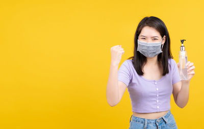 Portrait of beautiful young woman against yellow background