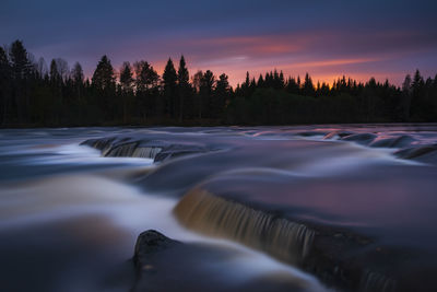 Misty water rushing over rocks at sunset