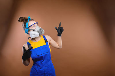 Young caucasian woman in construction uniform stands on a colored background
