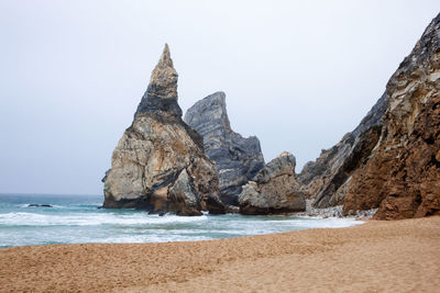 Rock formations on beach against clear sky