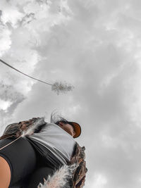 Low angle view of woman sitting against sky