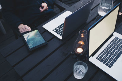 Woman using digital tablet by laptop on wooden table at holiday villa