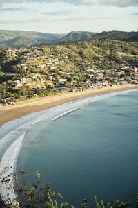 Aerial view of townscape by sea against sky