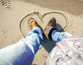 Low section of man wearing shoes on sand