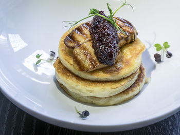 High angle view of pancakes with fried foie gras and onion marmalade on table