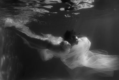 Woman with curtain swimming in pool