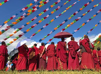 Monks wearing traditional clothing standing against flags and sky