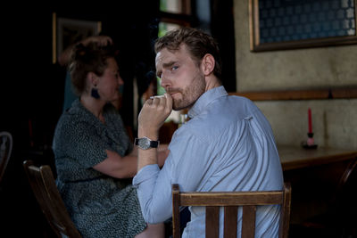 Side view of young man sitting on chair