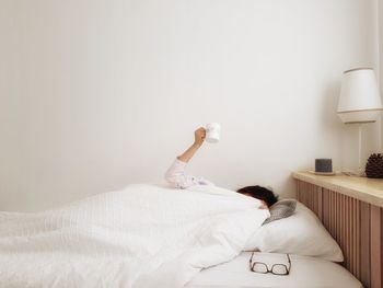 Woman with mug lying on bed at home