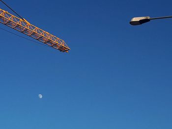 Street light, moon and cranes supervising a construction site