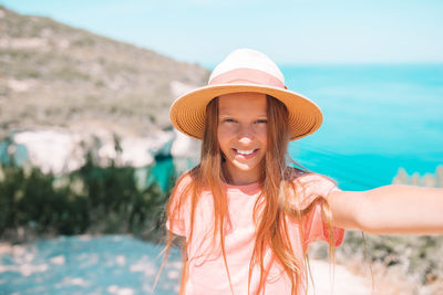 Portrait of young woman wearing hat standing at beach