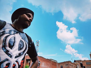 Low angle view of young man standing against sky