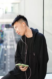 Young man looking away while listening music indoors