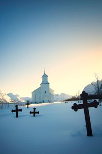 Church with snow covered cemetery in foreground against blue sky