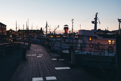 Sailboats moored at harbor against sky during sunset