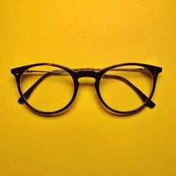 Close-up of eyeglasses on table against yellow background