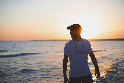 Man standing on beach against sky during sunset