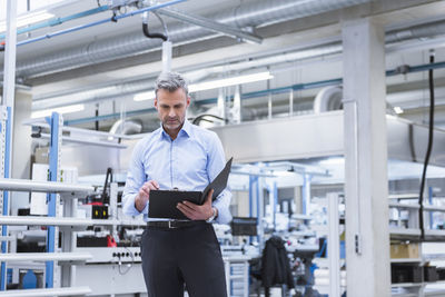 Manager with files walking through factory