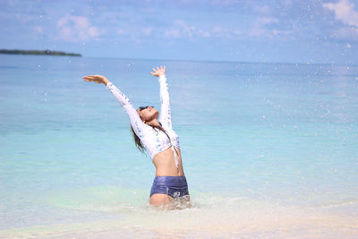 Woman with arms raised on beach