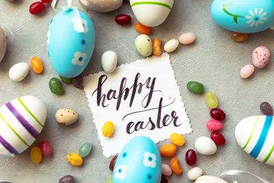 Easter eggs inscription happy easter candy chocolate eggs and jellybean sweets on grey background