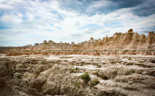 Rock formations on landscape against cloudy sky