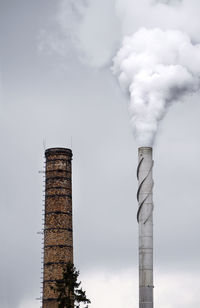 Low angle view of smoke emitting from chimney against sky