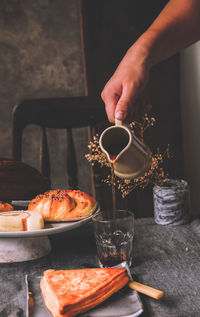 Close-up of person pouring drink in glass on table