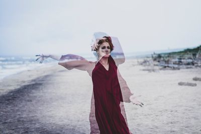 Blurred motion of woman standing at beach against clear sky