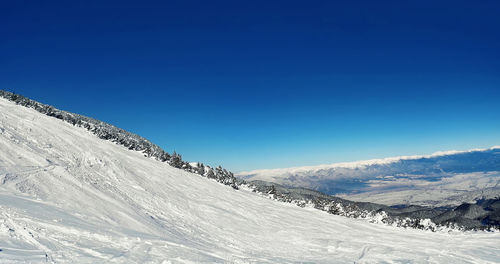 Scenic view of snowcapped mountains against clear blue sky
