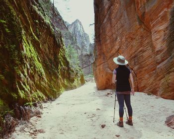 Rear view of woman standing amidst rock formation at zion national park