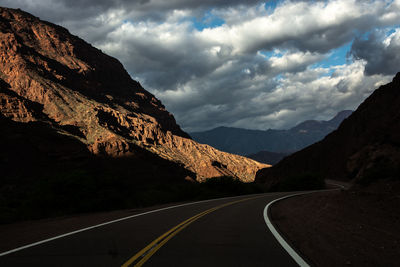 Road by mountains against sky