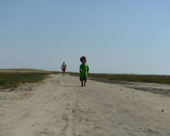 Full length of woman standing on grass walking after grand child boy