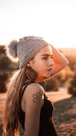 Portrait of young woman standing against clear sky