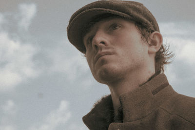 Portrait of young man looking away against sky