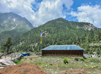 House by trees and mountains against sky