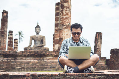 Asian tourist working and using laptop at sukhothai historical park, thailand