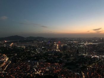 High angle view of illuminated city buildings against sky at sunset