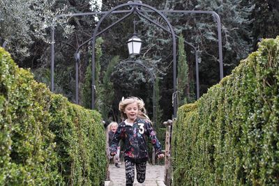 Siblings running amidst plants at park