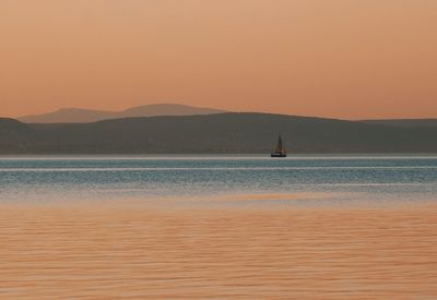 Silhouette of boat sailing in sea at sunset