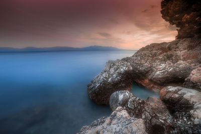 Close-up of rock by sea against sky during sunset