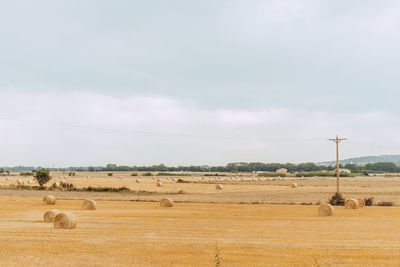 Hay bales on field against sky