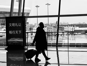Rear view of man standing by window at airport