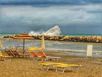 Chairs on beach by sea against sky