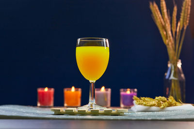 Glass of orange juice isolate on wooden plate with candlelight on table