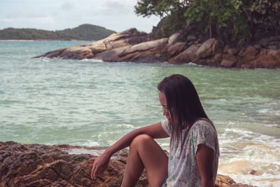 Woman sitting on rock at beach