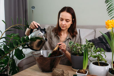 Portrait of smiling young woman holding potted plant on table