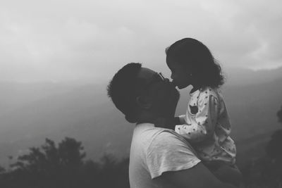 Side view of mother and daughter against sky