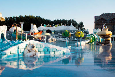 Swimming pool by lake against clear sky