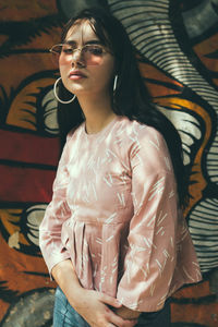 Portrait of woman wearing sunglasses against graffiti wall